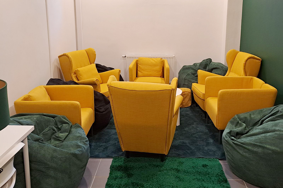 Pomieszczenie do relaksu z żółtymi fotelami, zielonymi pufami.