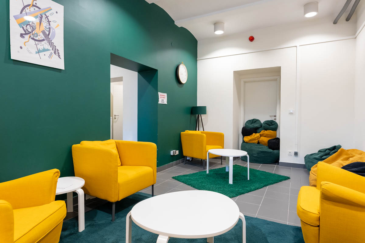 Przestrzeń w zielono-żółtych kolorach, z fotelami, stolikami i pufami.