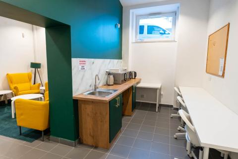 Wnęka kuchenna wyposażona w drewniane meble kuchenne, biały stół i krzesła.