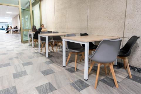 Przestrzeń Wydziału Farmaceutycznego, z szarymi i czarnymi krzesłami i stolikami.